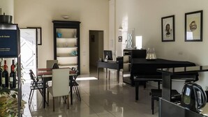 A spacious living area with a dining table, chairs, a black sofa, a coffee table, and a bookshelf. There are framed pictures on the wall and a television on a stand. - Villa Archi (Faenza)