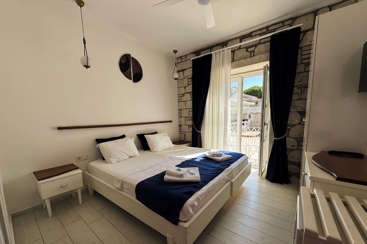 Un dormitorio con cama, mesita de noche, cómoda y vistas al exterior.