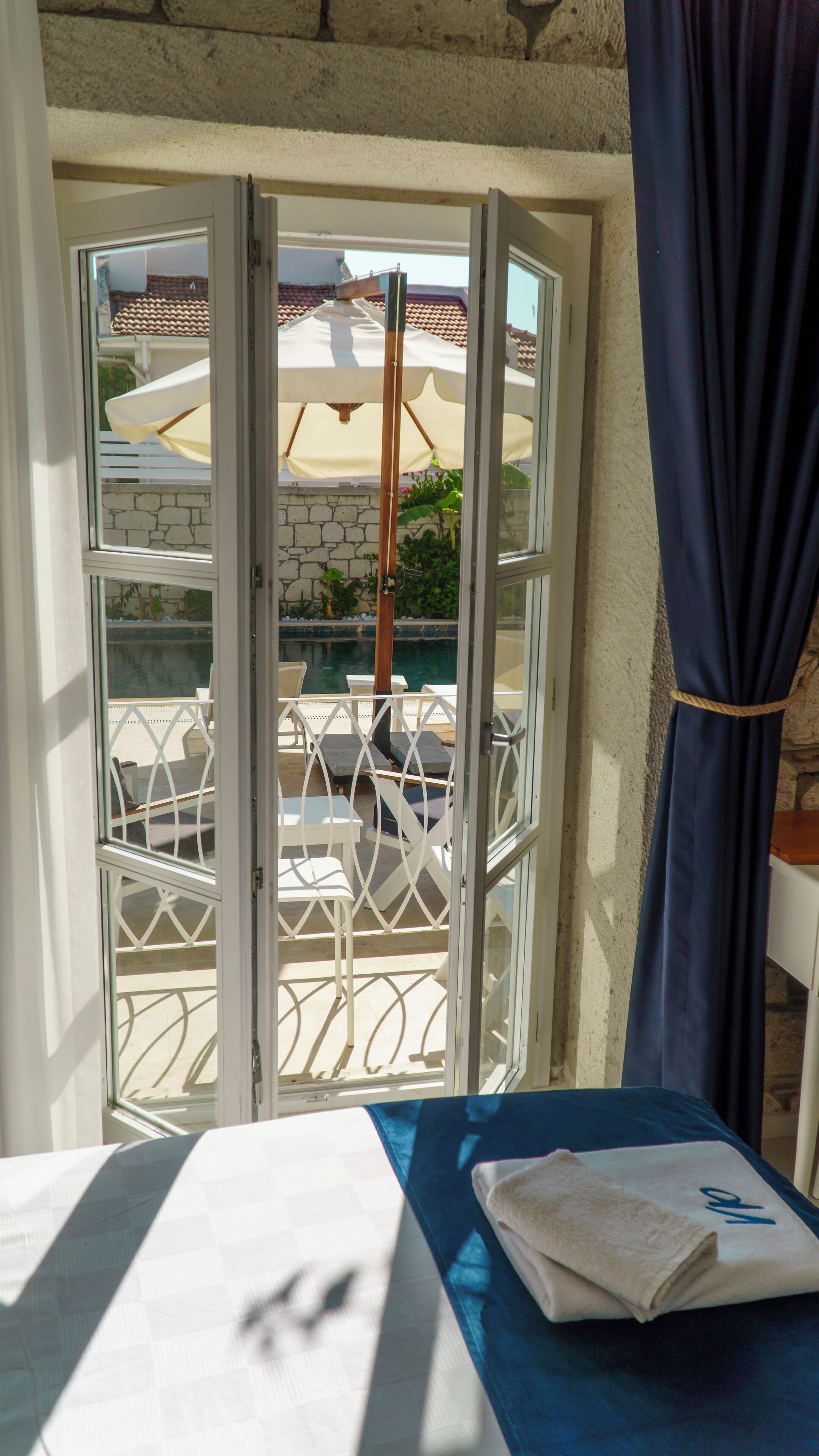 A room with a view of a pool area, a table with a towel, and a curtain.