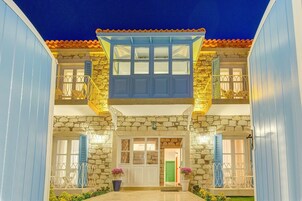 Una casa de dos pisos con fachada de piedra, contraventanas azules y tejado de tejas.