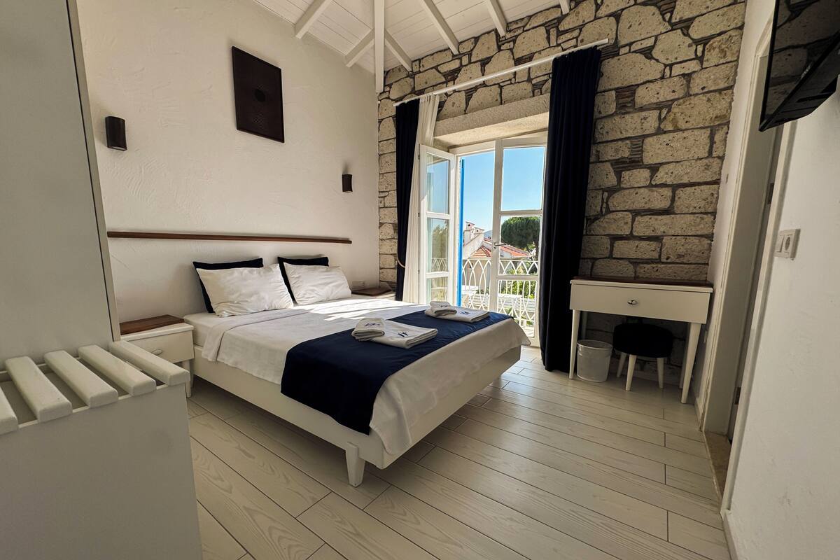 Un dormitorio con cama, escritorio y vistas al exterior.