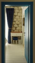 Una habitación con pared de piedra, un escritorio con silla y una puerta.