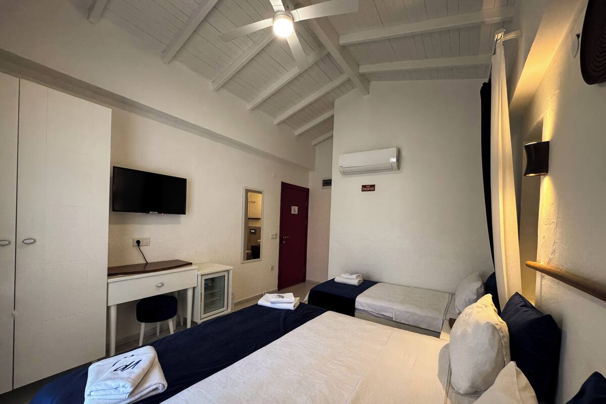 Una habitación de hotel con cama, escritorio, televisor y armario.