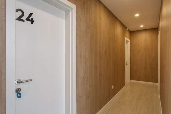 Un pasillo con paredes de madera y una puerta blanca con el número 24.