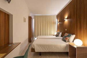 A hotel room with two beds, a desk, and a chair.