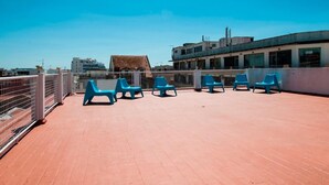 A rooftop terrace with blue plastic chairs and a metal fence.