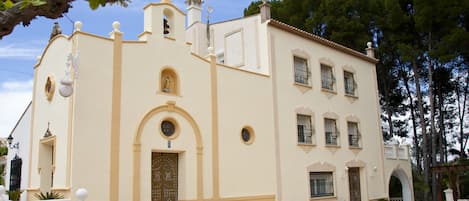 A building with a symmetrical facade, a central entrance with an arch, and a bell tower.