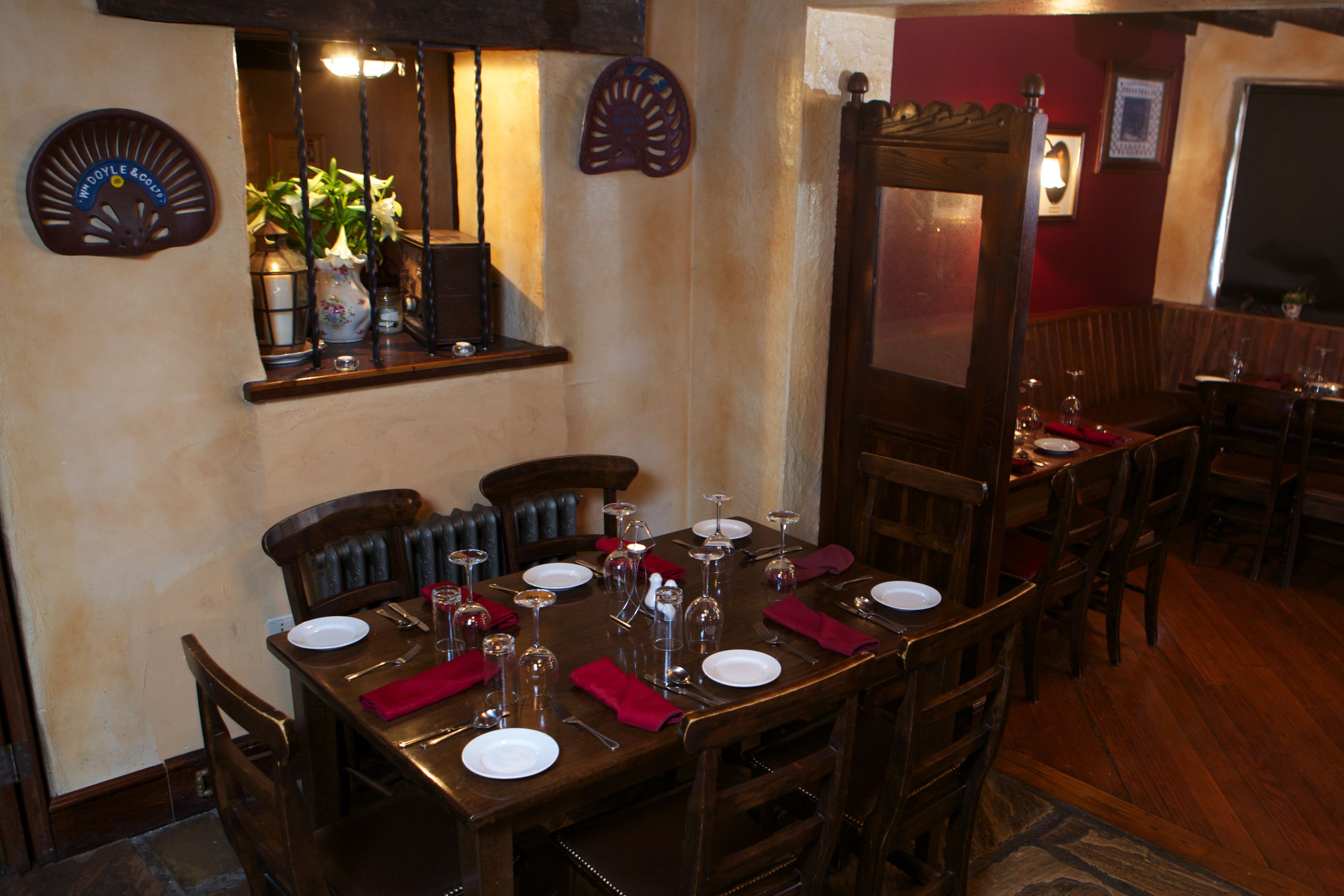 Un comedor con una mesa de madera dispuesta para cuatro personas, rodeado de sillas.