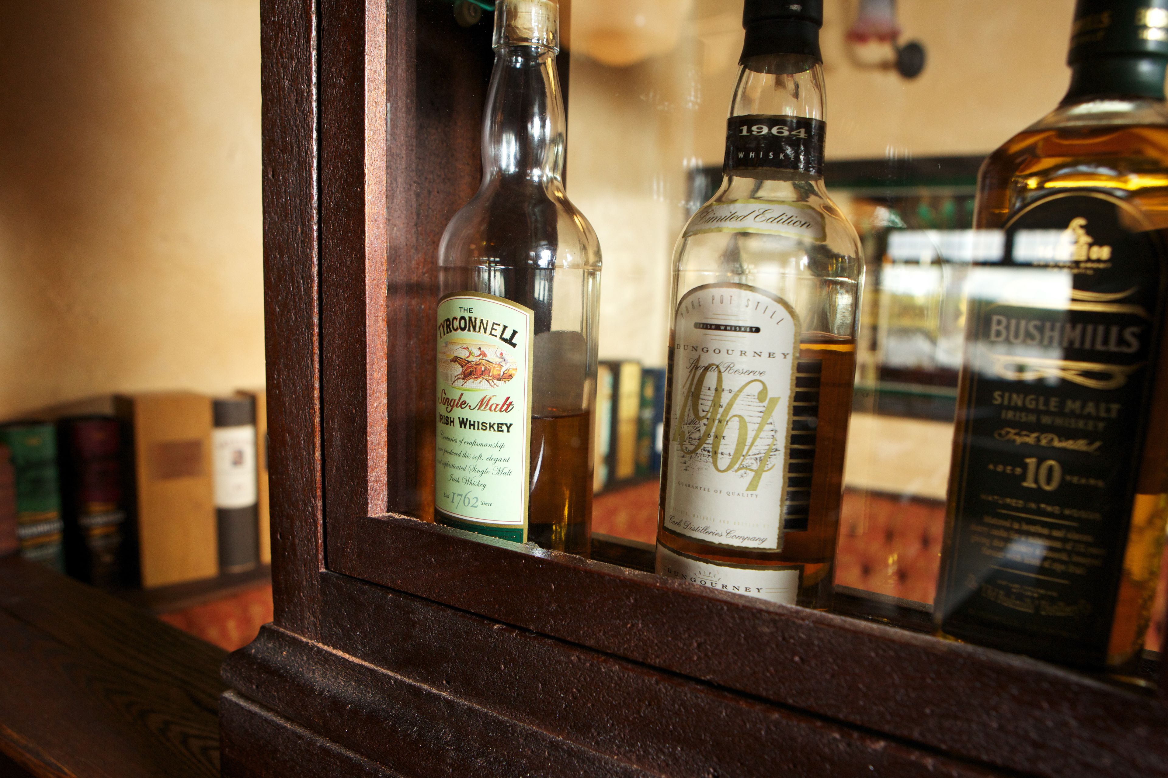 A selection of whiskey bottles in a wooden cabinet.