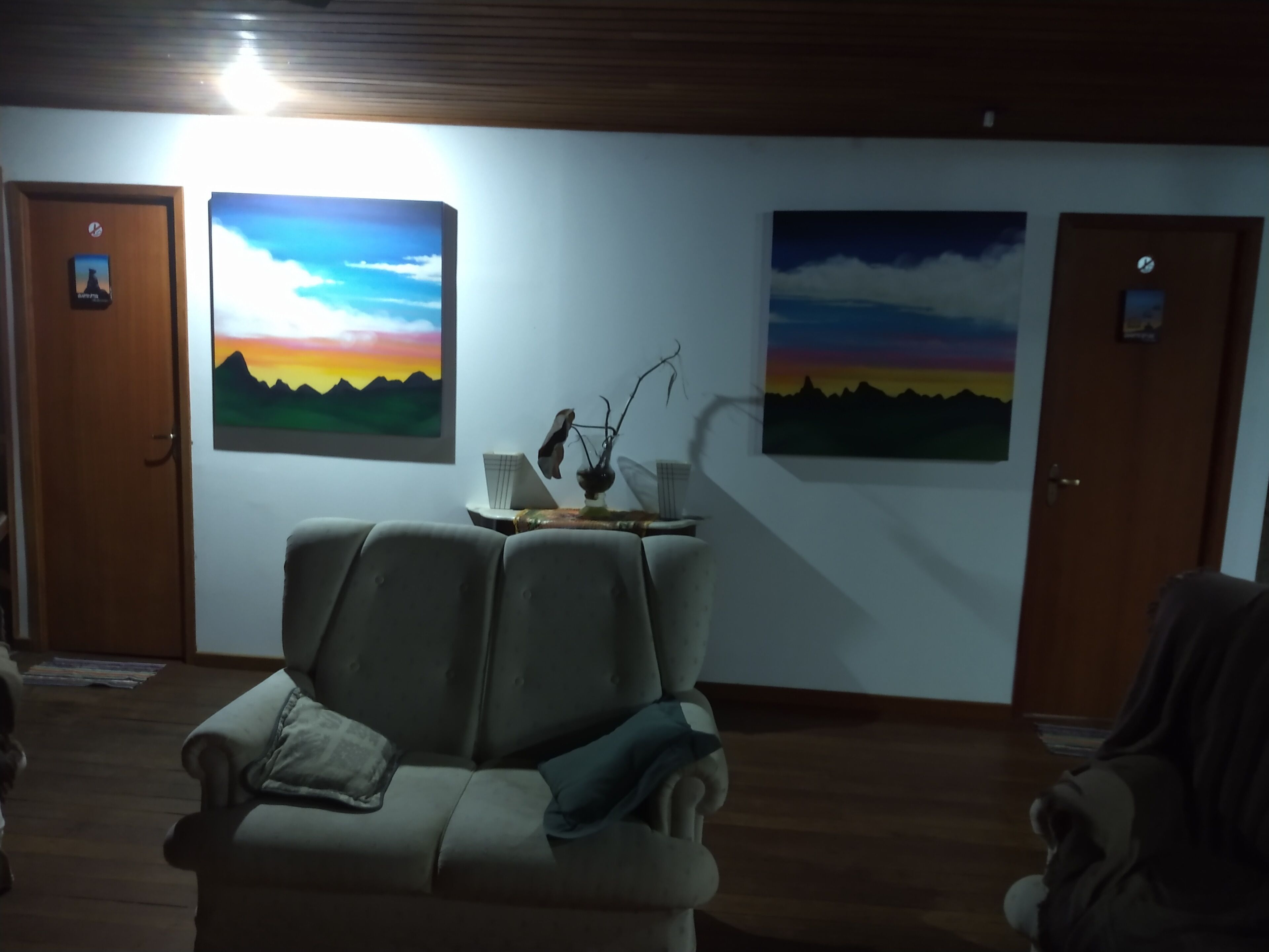 Una habitación con un sofá, dos puertas y dos cuadros en la pared.