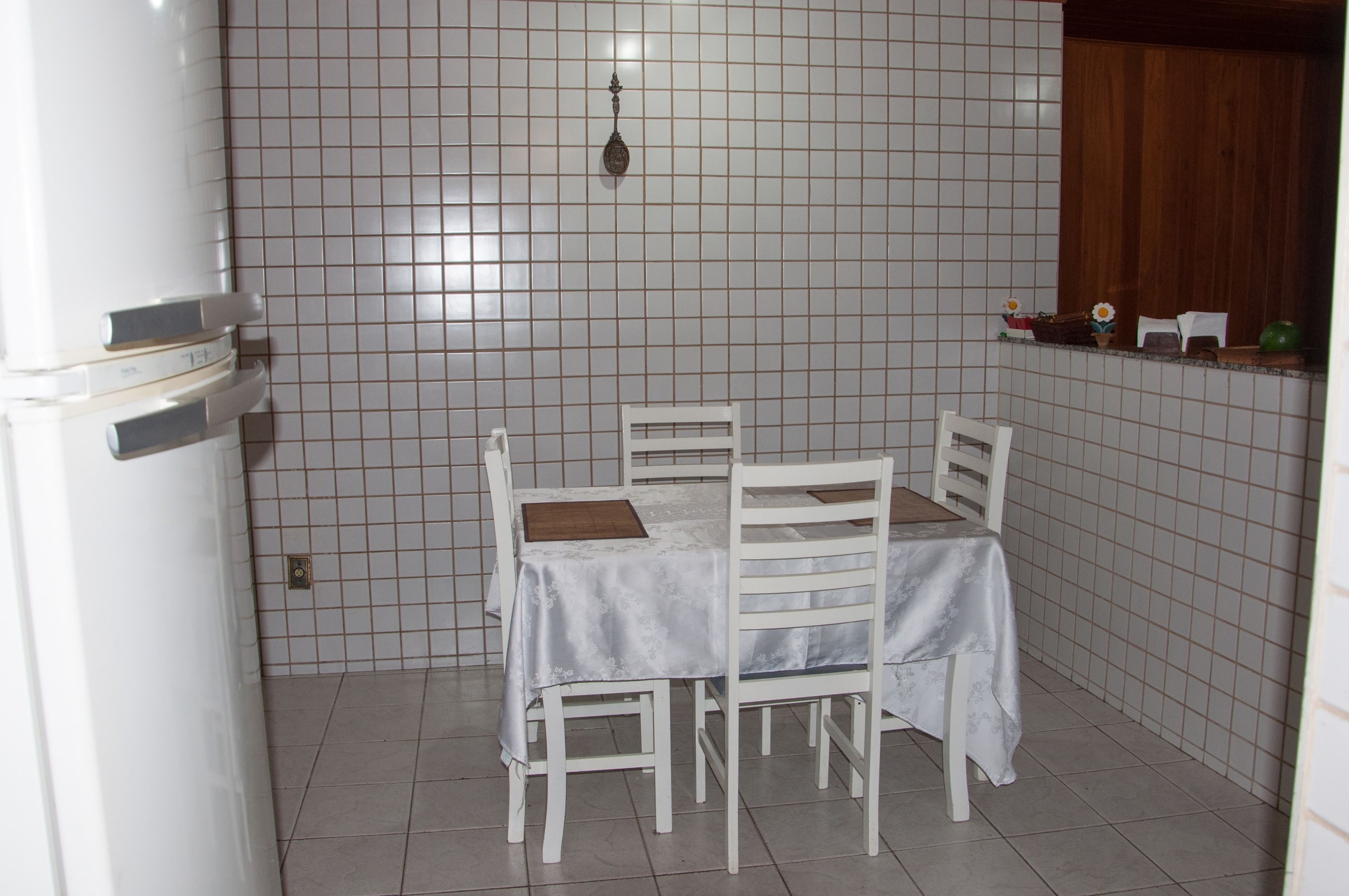 A small dining area with a table and chairs, a white refrigerator, and a tiled backsplash.