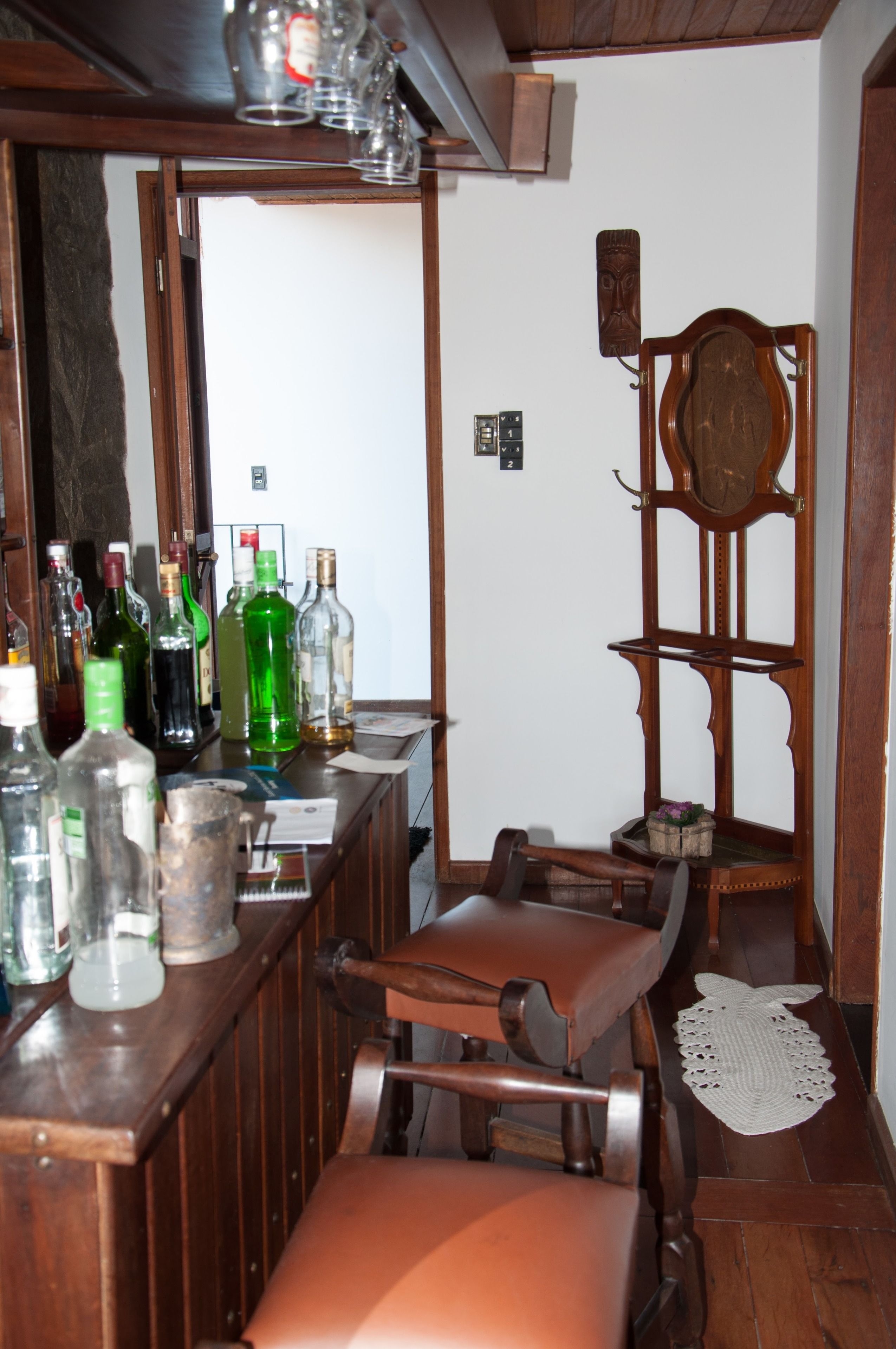 Una zona de bar con mobiliario de madera, un espejo y varias botellas.