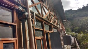 Un edificio con grandes ventanales y vigas de madera, rodeado de vegetación.
