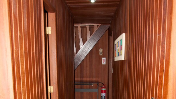 A wooden hallway with a staircase, a fire extinguisher, and a framed picture on the wall. - 746 Pousada (Nova Friburgo)