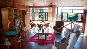 Una habitación con paneles de madera, una mesa de comedor, sillas, un sofá y un televisor.