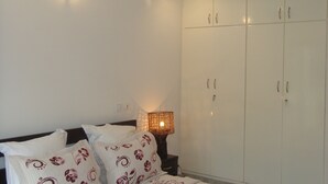 A bedroom with a bed, a bedside lamp, and a wardrobe. - Ernaa Chambres D'Hotes (Abidjan)