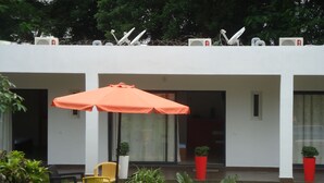 A modern building with a covered patio area featuring outdoor seating and potted plants. - Ernaa Chambres D'Hotes (Abidjan)