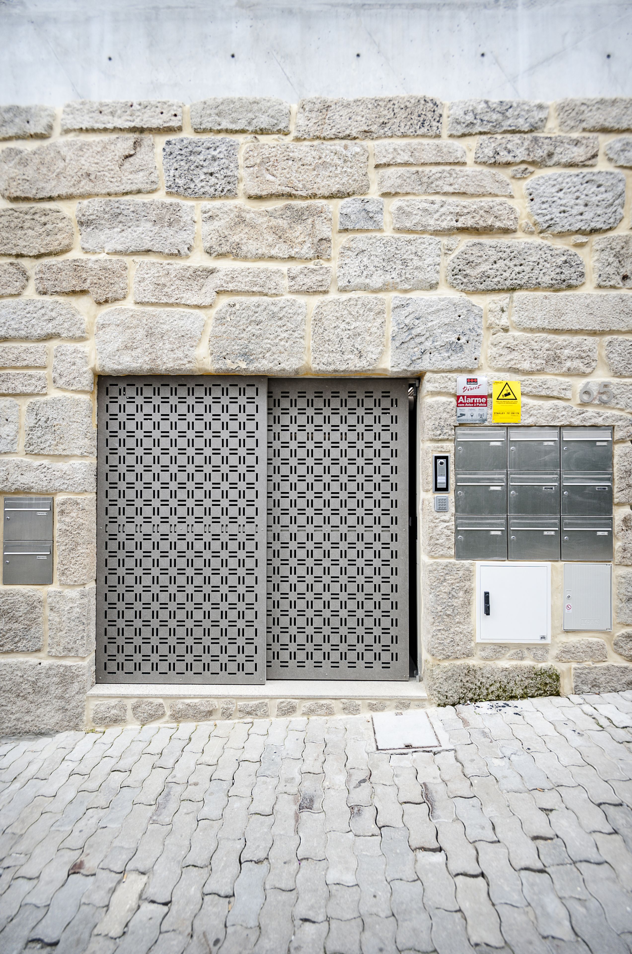 Un mur de pierre avec une porte en métal et une série de boîtes aux lettres.