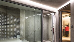 A modern interior with a glass partition, a concrete wall, and a door leading to another room. - PortoSoul Trindade (Porto)