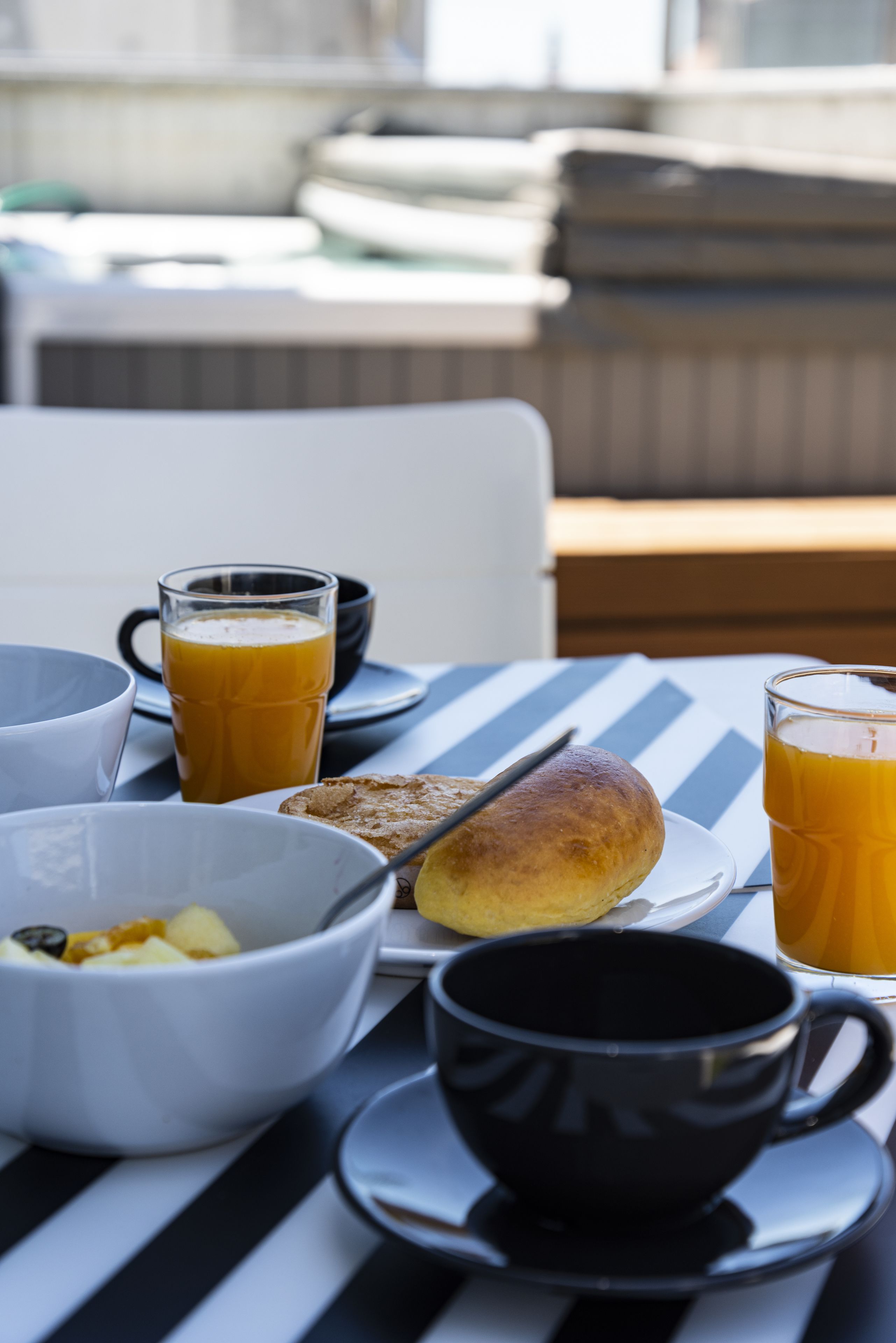 Una tavola imbandita per la colazione, con una ciotola di frutta, un cornetto e due bicchieri di succo d'arancia.