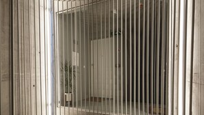 A corridor with a series of vertical bars, a concrete floor, and a door at the end. - PortoSoul Trindade (Porto)