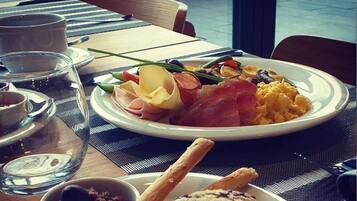 A breakfast setting with a plate of food, a glass of water, and a cup on a table.
