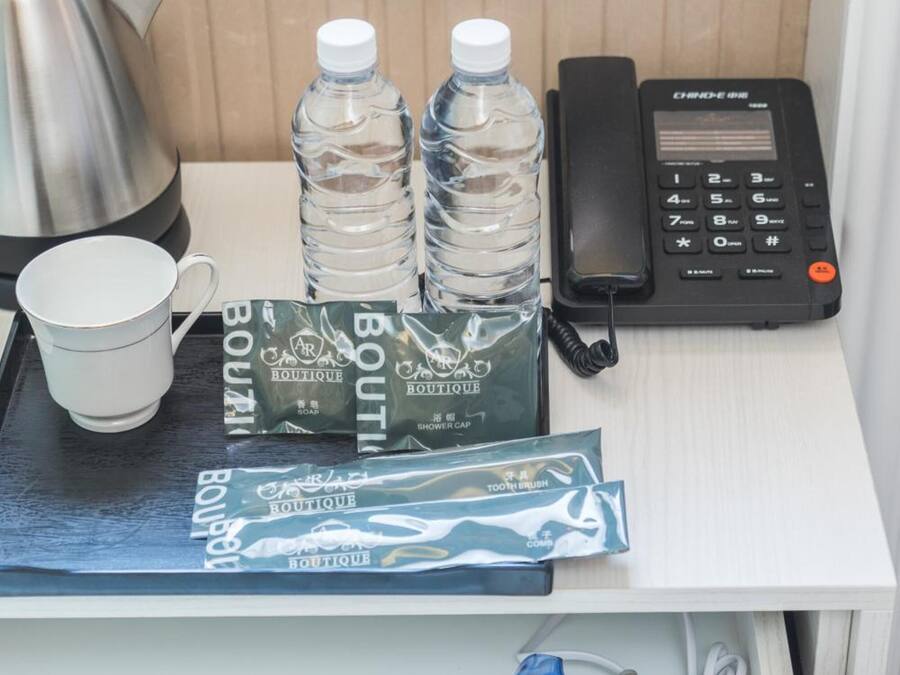 A hotel room with a minibar, a kettle, bottled water, a phone, and toiletries.