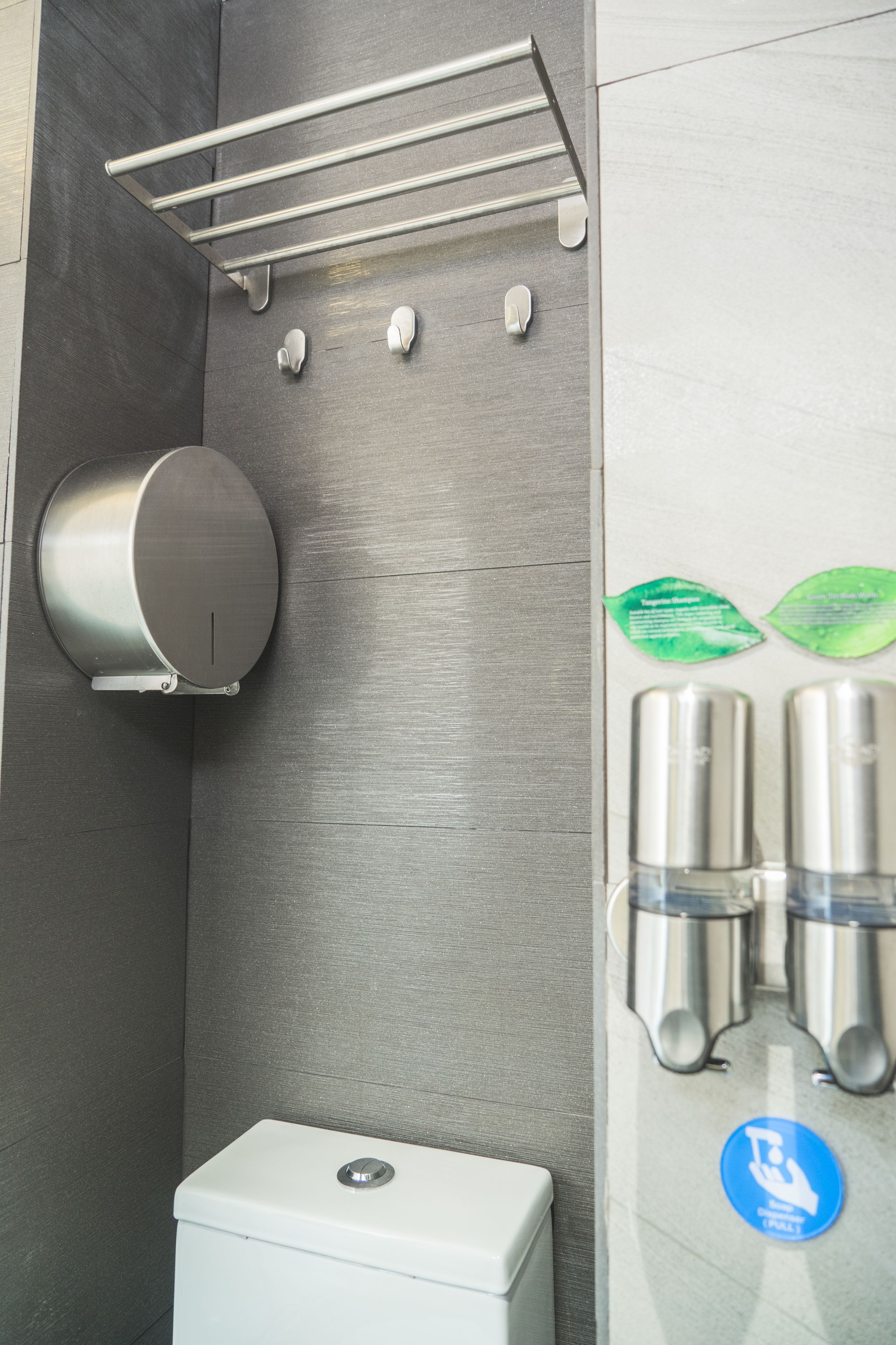 A modern restroom with a toilet, hand dryer, and paper towel dispenser.