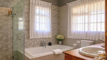 A bathroom with a glass-enclosed shower, a freestanding bathtub, and a vanity with a sink.