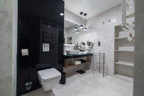 A modern bathroom with a white toilet, a glass sink, and a black vanity.