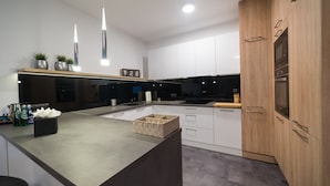 A modern kitchen with white cabinets, a wooden countertop, and pendant lights. - Apart-Hotel VIVI Residence & SPA (Zory)