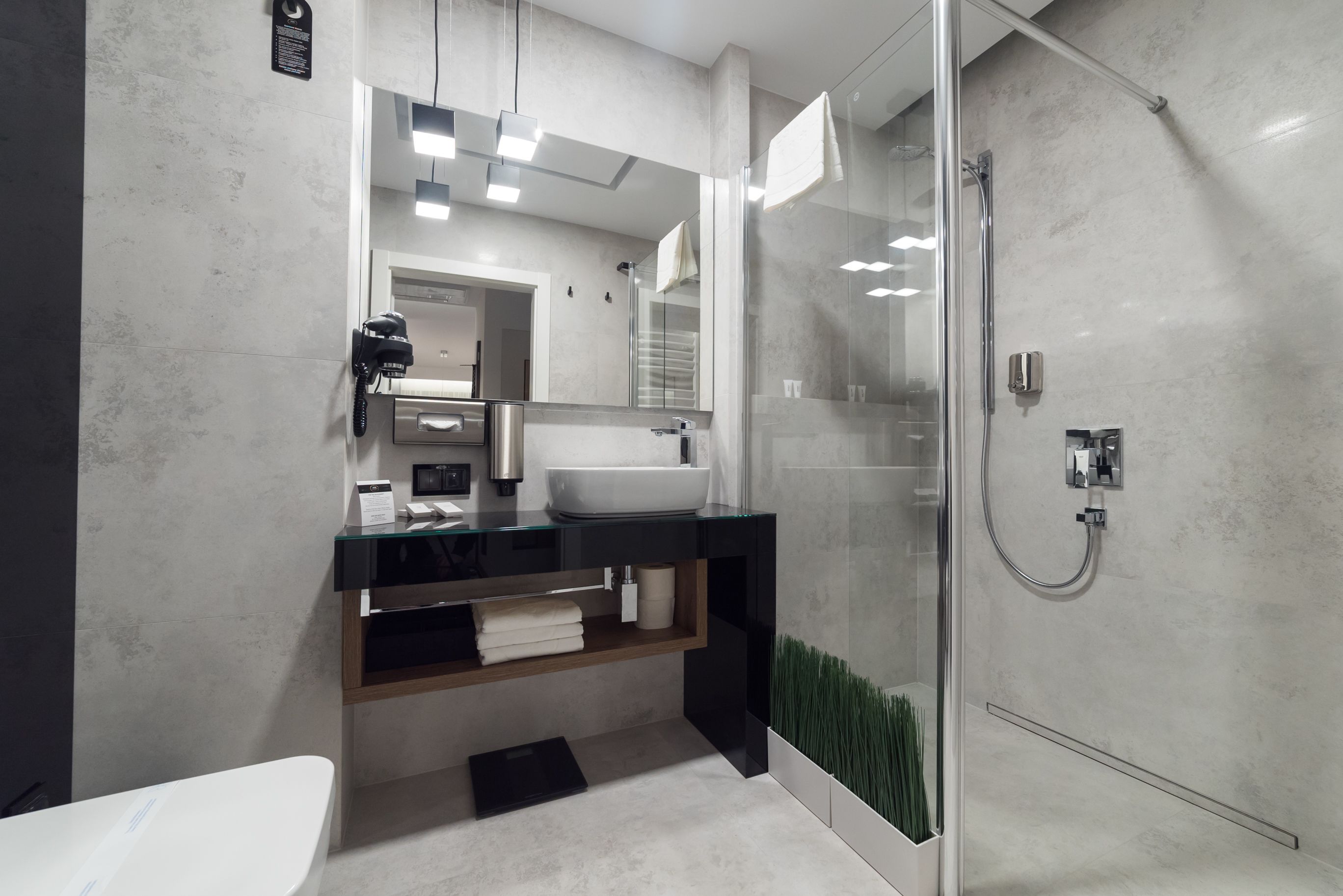 A modern bathroom with a glass shower enclosure, a white sink, and a built-in vanity with a mirror.