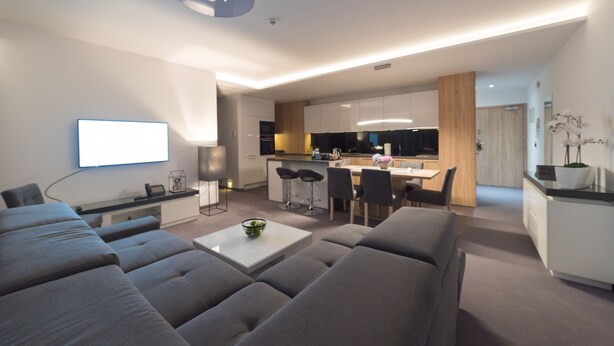A modern living room with a sofa set, a coffee table, and a TV mounted on the wall. - Apart-Hotel VIVI Residence & SPA (Zory)