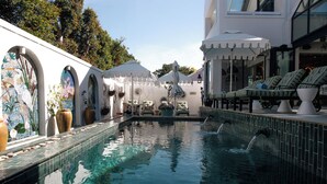 Ein Pool mit einer gefliesten Kante, Liegestühlen und Topfpflanzen.
