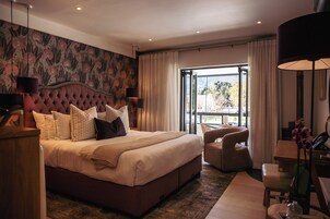 Habitación de hotel con una cama grande, un escritorio, una silla y vistas al exterior.