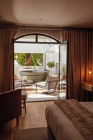 A bedroom with a large bed, a desk, and a view of an outdoor area with a boat and greenery.