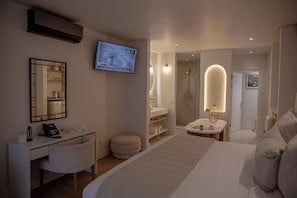 Een hotelkamer met een bed, een bureau met telefoon, een televisie, een badkamer met douche en een spiegel.