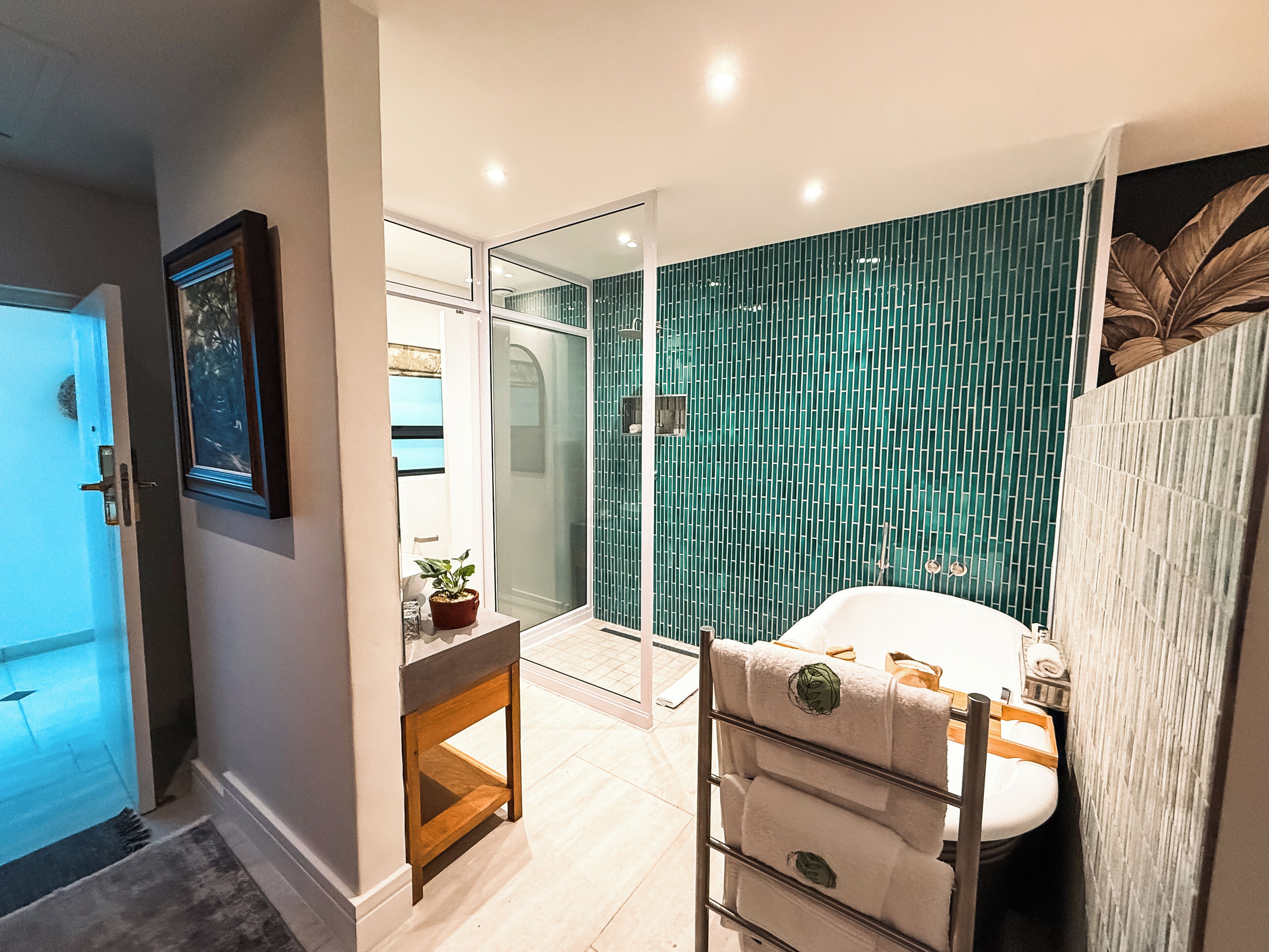 Een moderne badkamer met een douchecabine van glas, een witte wastafel en een houten opbergmeubel.