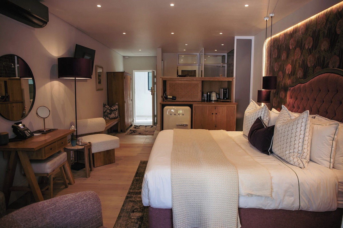 A modern bedroom with a large bed, bedside tables, a desk, and a wardrobe.