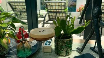 A table with a cactus plant, a bottle, a glass with a drink, and a small figurine.