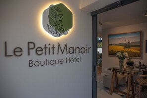 A hotel sign with a logo and the name 'Le Petit Manoir Boutique Hotel'.