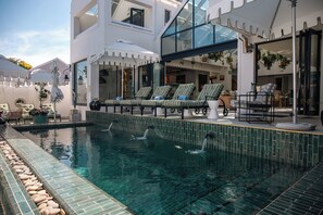 A modern outdoor pool area with lounge chairs and a glass-enclosed building.