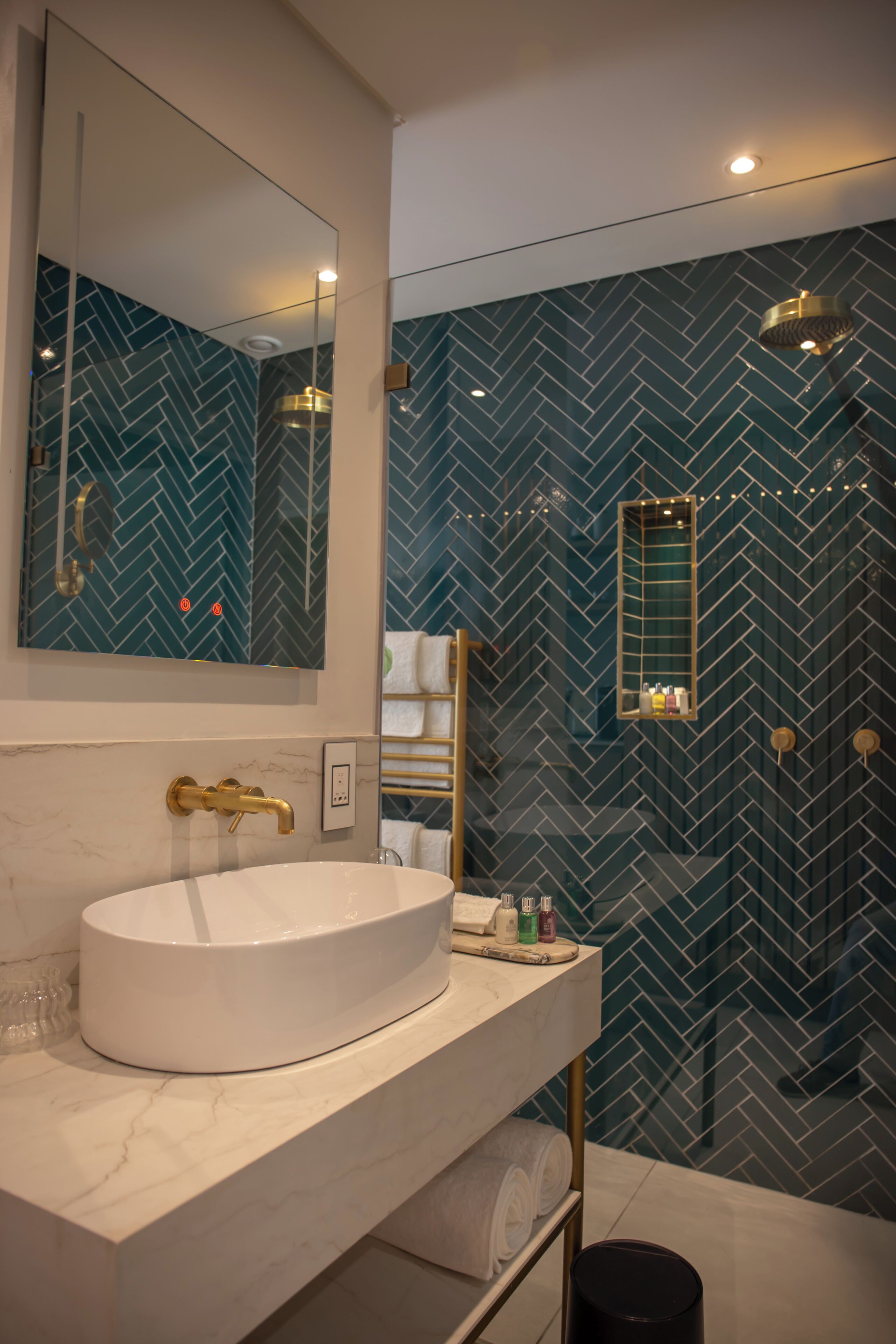 Ein modernes Badezimmer mit einem großen, weißen Waschbecken, einem goldenen Wasserhahn und einem Spiegel darüber.