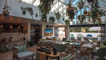 Amplio espacio interior con plantas colgantes, arreglos de asientos y vistas a través de un techo de cristal.