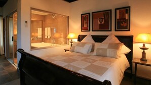 A hotel room with a large bed, two bedside lamps, a mirror, and three framed artworks on the wall. - Pensao Guest Lodge (Mbombela)