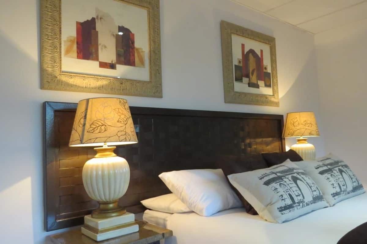 A hotel room with a large bed, two bedside lamps, and framed artwork on the wall.