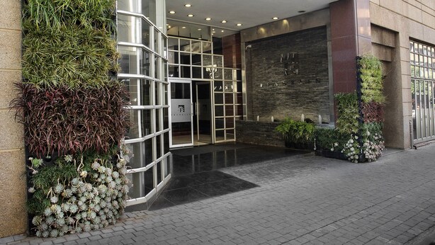 Une entrée moderne avec une porte en verre, une façade en briques et un petit espace jardin agrémenté de plantes.