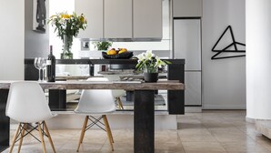 Une cuisine moderne avec un îlot central, des chaises blanches et un vase rempli de fleurs.