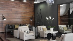Un salon moderne avec un mur en bois, des canapés gris, une table basse ronde et un lustre.