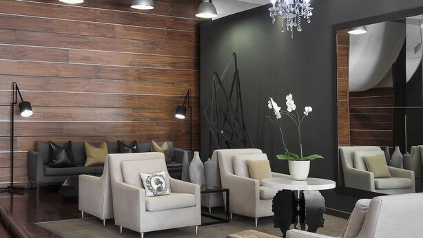 Un salon moderne avec un mur en bois, des canapés gris, une table basse ronde et un lustre.